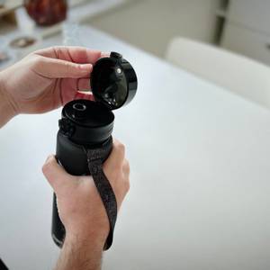 Die Trinkflasche ist offen und der Deckel wird von einer Hand festgehalten.