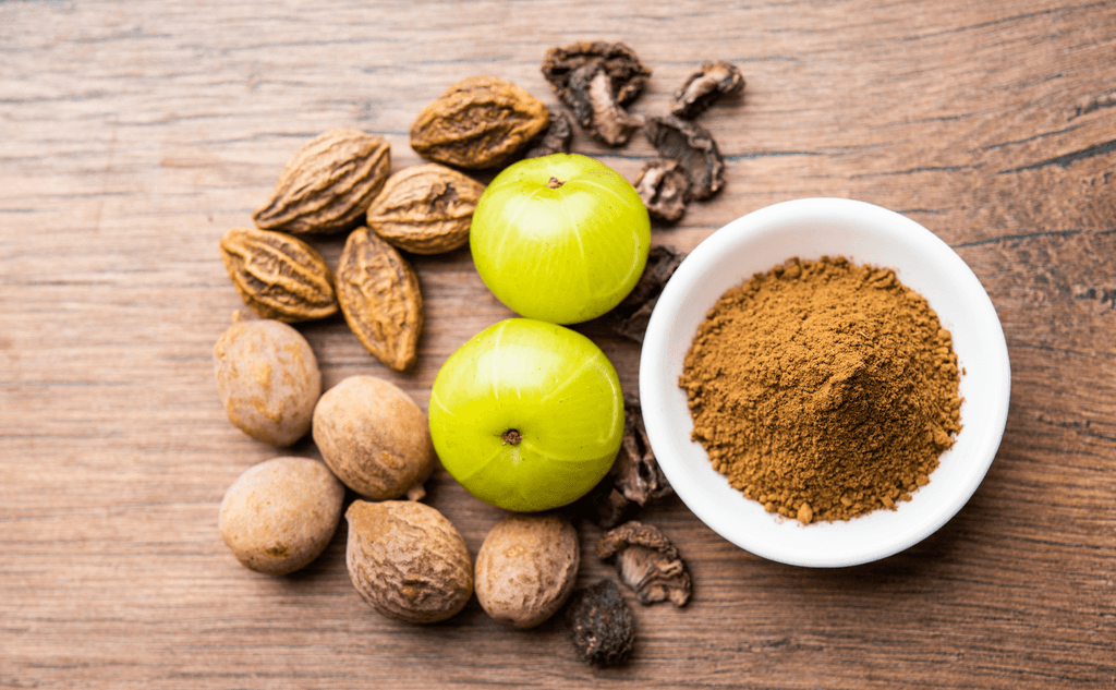 Triphala-Test: Vollaufnahme der Zutaten von Triphala auf einer Holzfläche. 