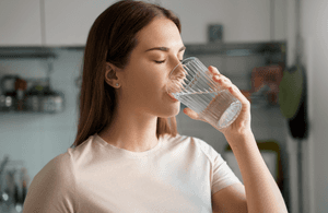 Triphala-Test: Eine Frau trinkt Wasser aus einem Glas. 