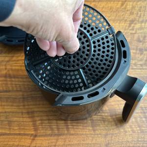 Eine Hand entfernt einen Einsatz aus dem Behälter der Tristar FR-6980.