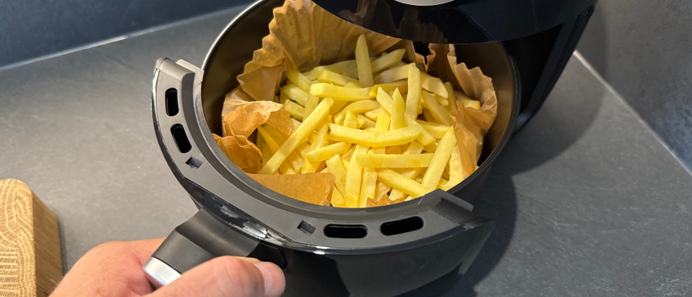 Eine Hand entfernt den Behälter der Tristar FR-6980 mit Pommes.