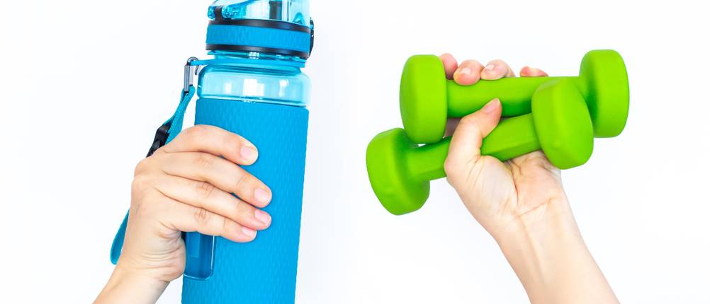 Tritan-Trinkflasche-Test: Eine blaue Trinkflasche und kleine grüne Hanteln werden gehalten.