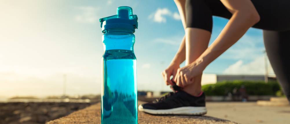 Tritan-Trinkflasche-Test: Eine Frau bindet sich den Schuh neben einer Tritan-Trinkflasche.