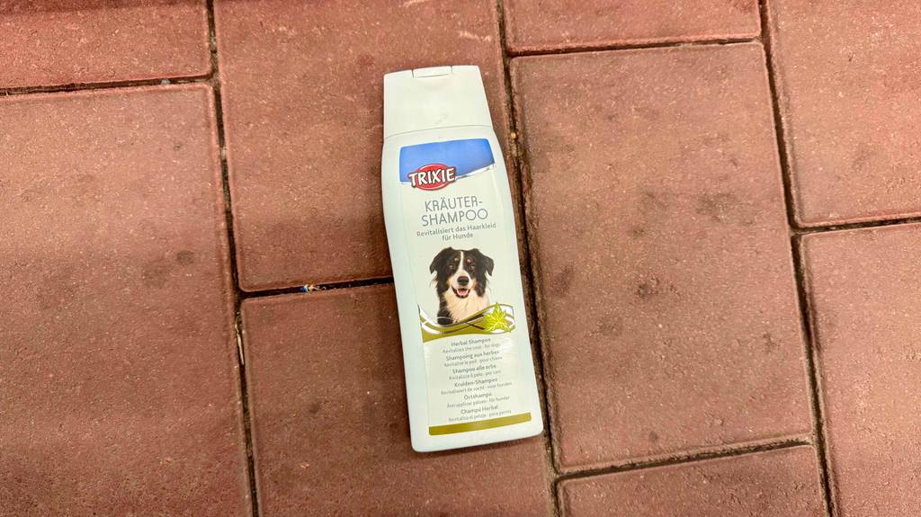 1 Flasche getestetes Trixie-Hundeshampoo liegt auf einem Steinboden.