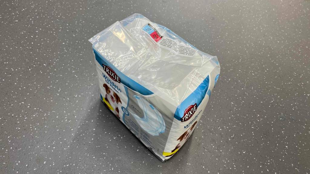 Eine Verpackung mit getesteten Trixie-Hundewindeln für Rüden steht auf einer grauen Oberfläche.
