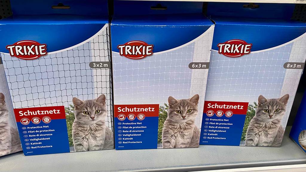 Katzennetz im Test: drei verschiedene Größen der Marke Trixie stehen nebeneinander in einem Regal.