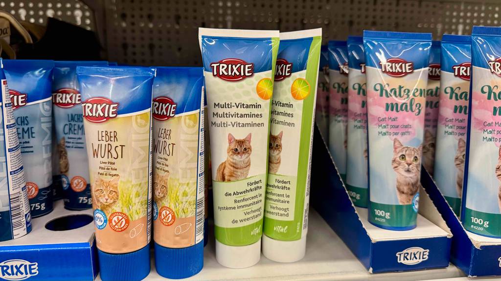 Vitamine für Katzen im Test: Mehrere Tuben stehen zwischen anderen Katzenleckereien in einem Regal.