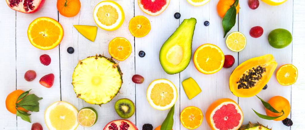 Papain-Test: Verschiedene tropische Früchte wie Ananas, Orangen, Avocados, Kiwis und Mangos liegen aufgeschnitten auf einem Tisch. 