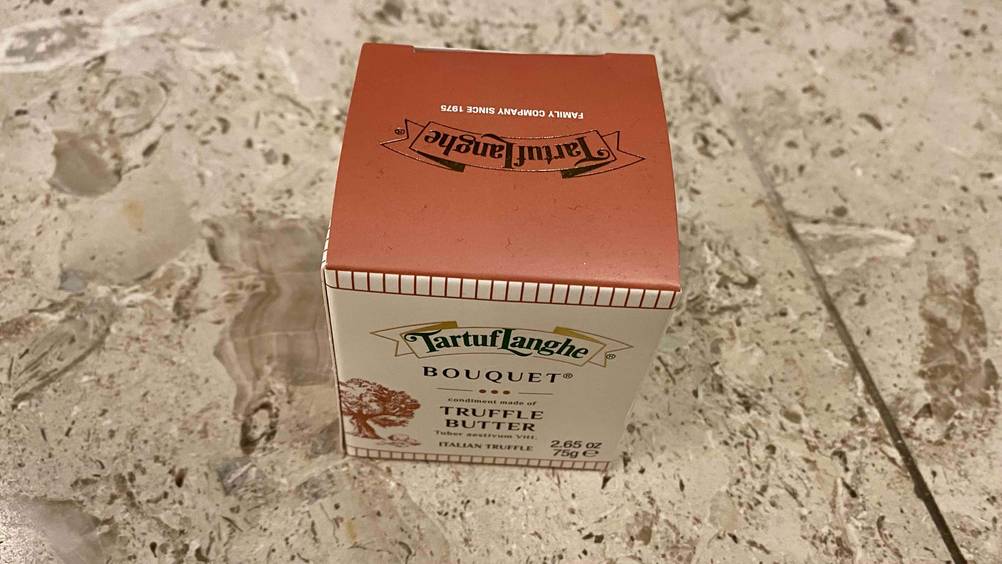 Verpackung von einer getesteten Trüffelbutter steht auf dem Boden.