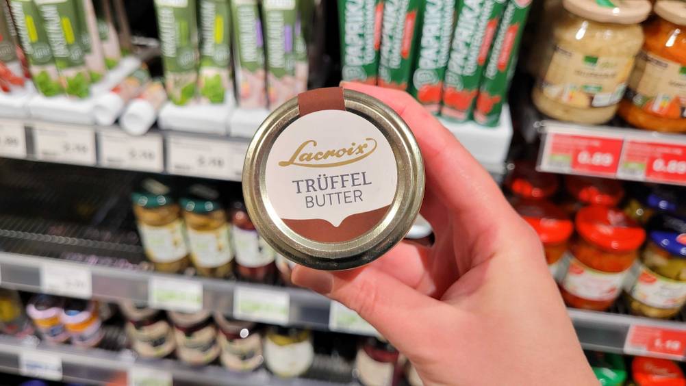 Eine Hand hält eine Dose der getesteten Trüffelbutter vor ein Verkaufsregal.