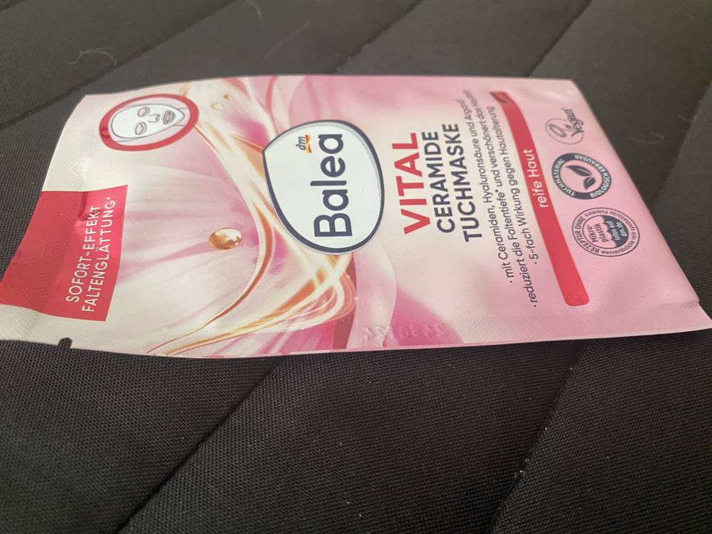 Im Test: Eine Tuchmaske in ihrer Verpackung auf einem dunklen Untergrund liegend.