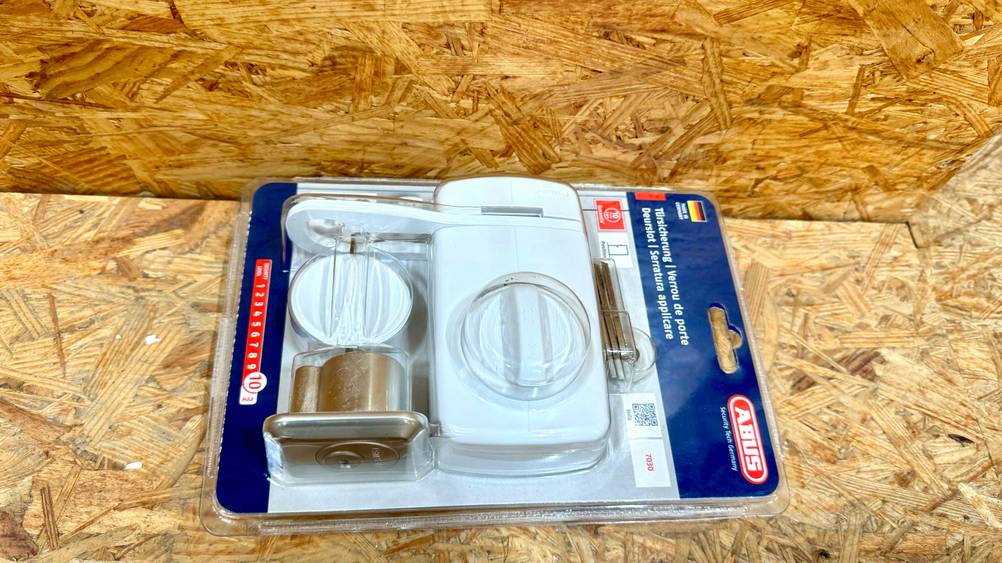 Getestet: Ein Tür-Zusatzschloss in Originalverpackung von der Seite auf Holz liegend.