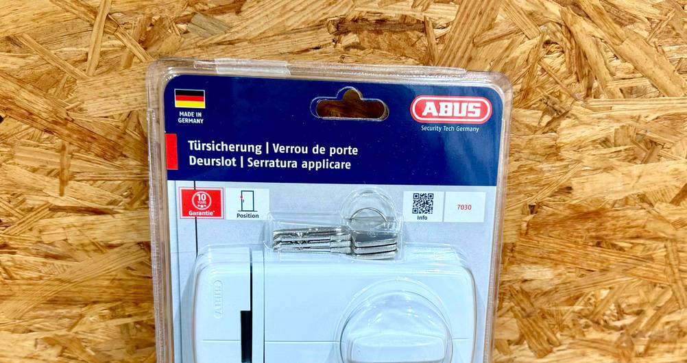 Nahaufnahme des Logos und der Artikelbezeichung auf dem originalverpackten Tür-Zusatzschloss im Test.