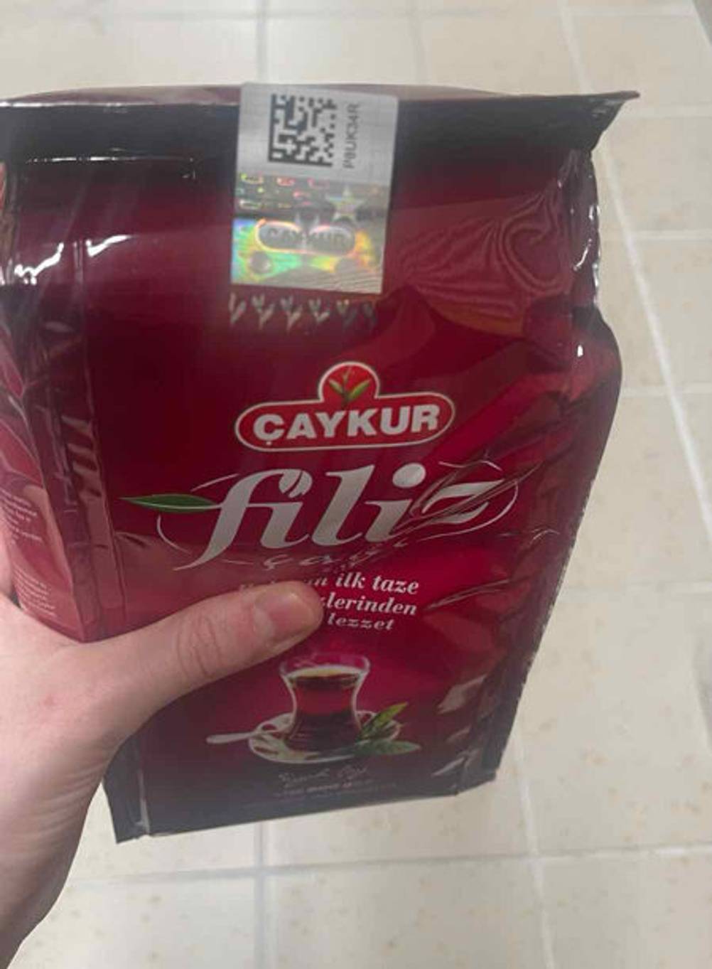 Der in einer Hand liegende, getestete, türkische Tee in der roten Verpackung ist mit einem Frischsiegel versehen.