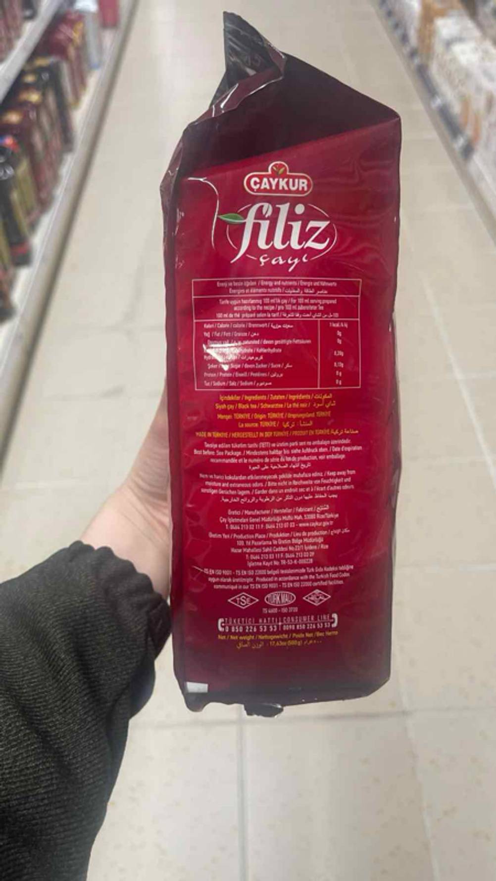 Eine Hand hält den getesteten türkischen Tee in einer roten Verpackung mit Produktangaben.