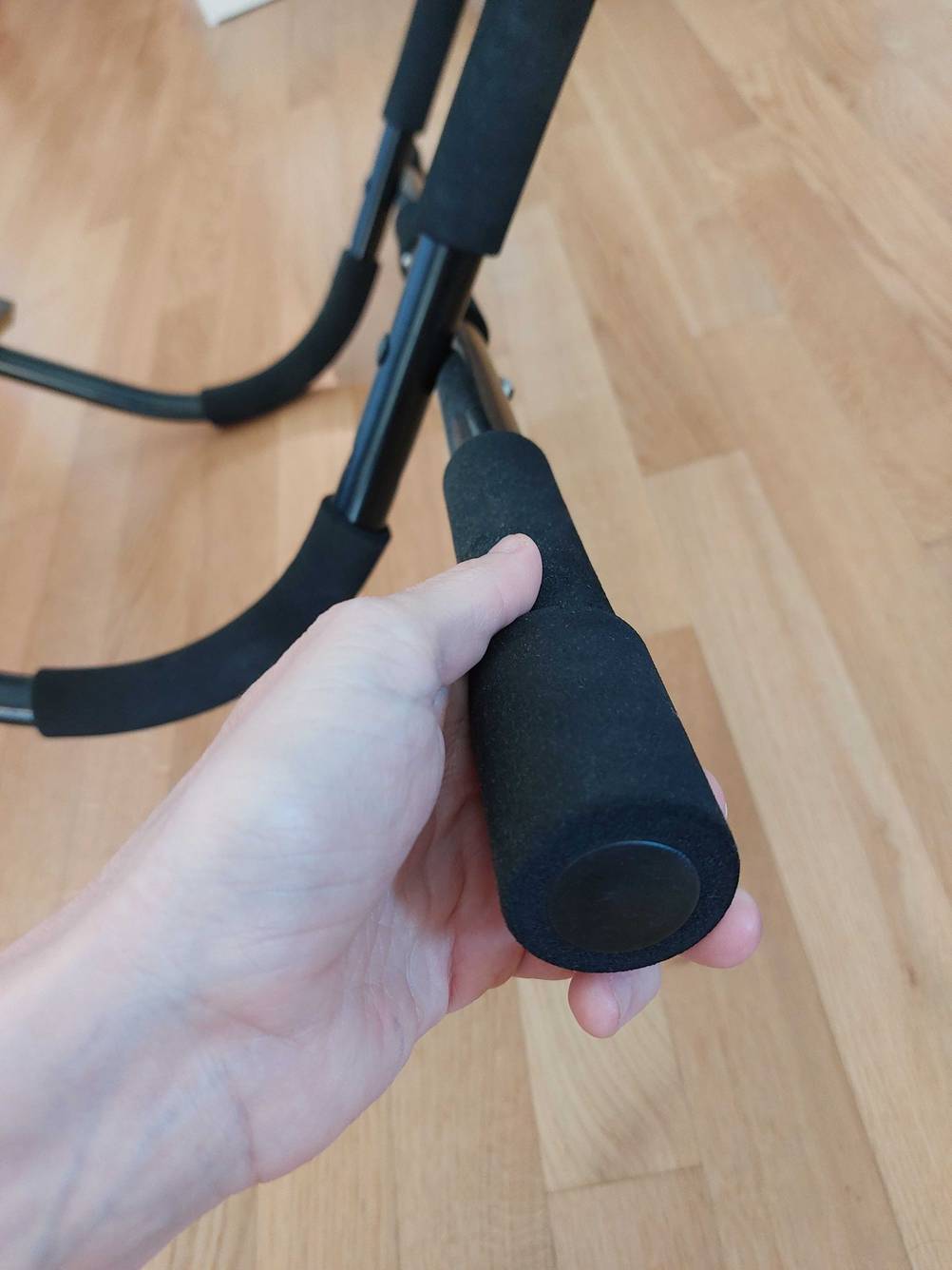 Im Test: Eine Hand hält den Griff einer Klimmzugstange für den Türrahmen.