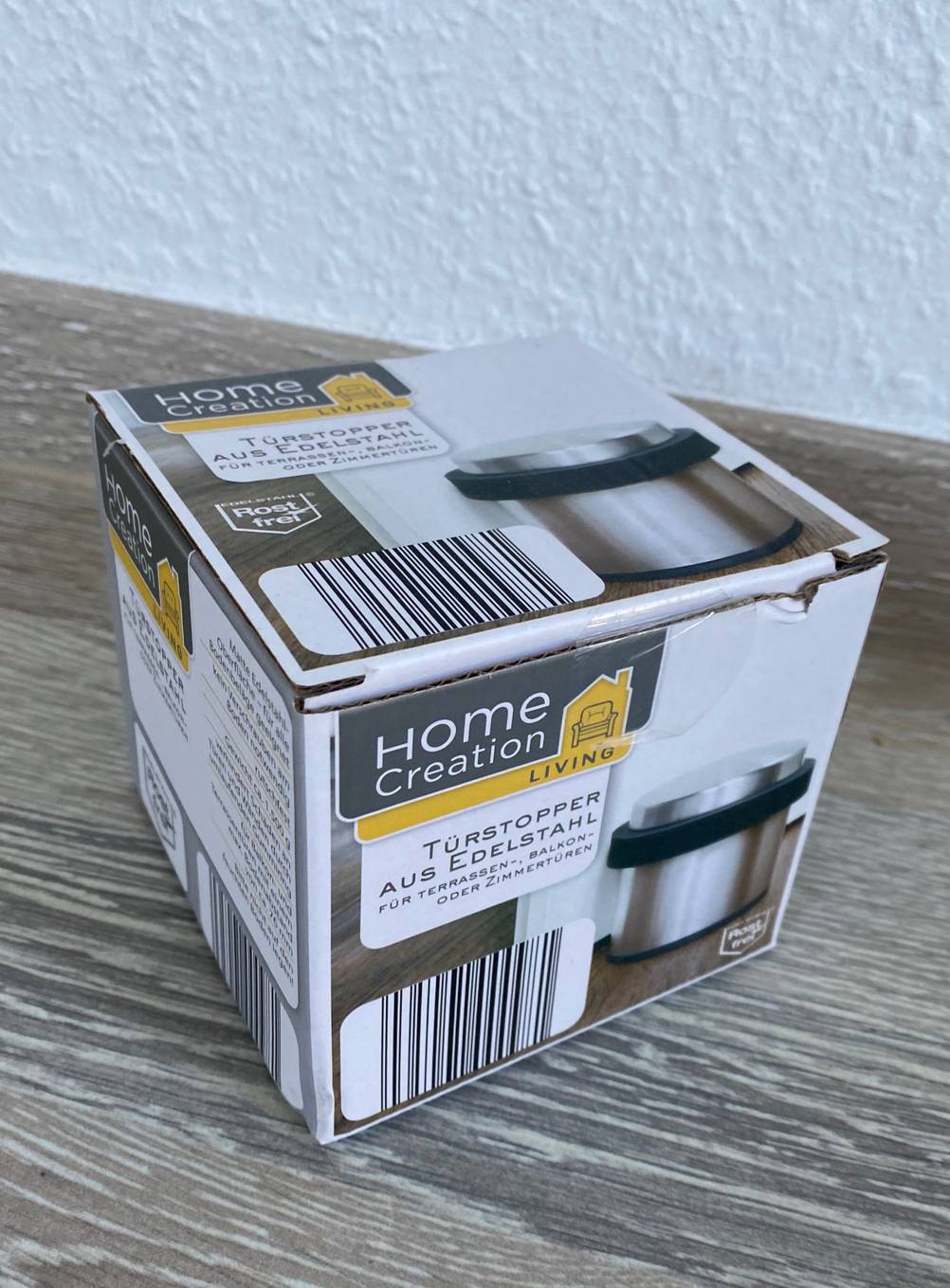 Ein originalverpackter Türstopper im Test vor einer hellen Wand auf einem Holztisch.