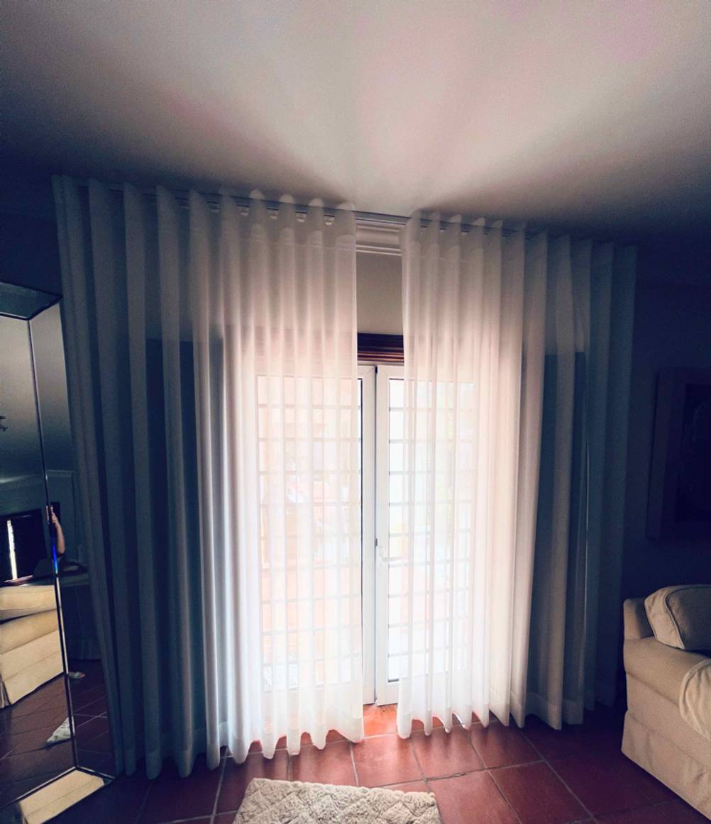 Ein Türvorhang im Test: Ein weißer Türvorhang ist im Wohnzimmer an den Fenstern angebracht.