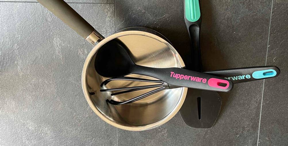Im Test: ein Küchenhelfer-Set in Schwarz von Tupperware in einem Milchtopf auf einer grauen Oberfläche.
