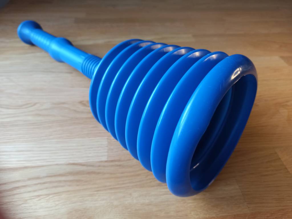 Ein blauer Pömpel auf einem Holzuntergrund liegend.