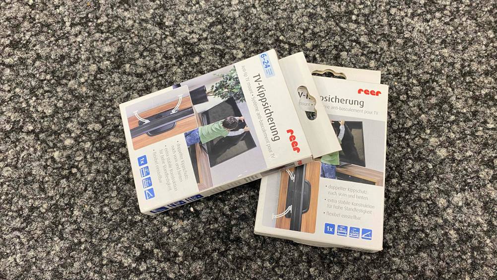 TV-Kippsicherung im Test: Zwei verpackte TV-Kippsicherung befinden sich auf dem Boden. 