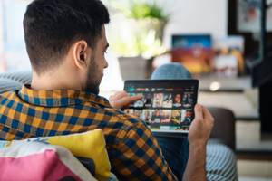 Online-TV-Test: Ein Mann sucht auf seinem Tablet einen Film aus, während er durch die Online-TV-App scrollt.