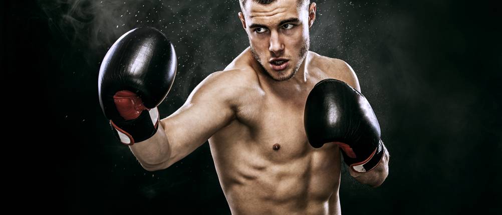 Twins-Boxhandschuhe im Test: Boxer oberkörperfrei mit Boxhandschuhen steht in Kampfposition da.