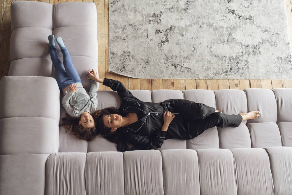 U-Sofa-Test: Zu sehen ist ein großes graues U-Sofa, auf dem eine Mutter und ihre Tochter bequem liegen.