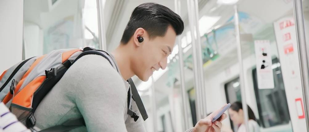 Übersetzungskopfhörer im Test: Ein Mann nutzt Bluetooth-Kopfhörer mit einem Smartphone und schaut auf das Display.