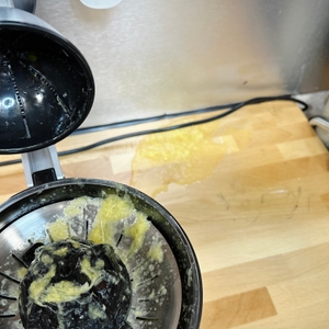 Die Ufesa Zitruspresse EX4950 nach der Nutzung mit ausgelaufenem Saft auf der Arbeitsplatte. Der Presskegel und das Sieb sind geöffnet, Tresterreste sind sichtbar.