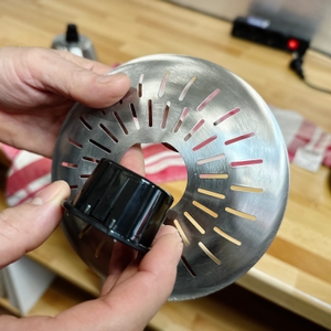 Eine Person hält das abnehmbare Edelstahl-Sieb der Ufesa Zitruspresse EX4950 in den Händen. Das Sieb hat feine Schlitze für die Trennung von Saft und Fruchtfleisch.