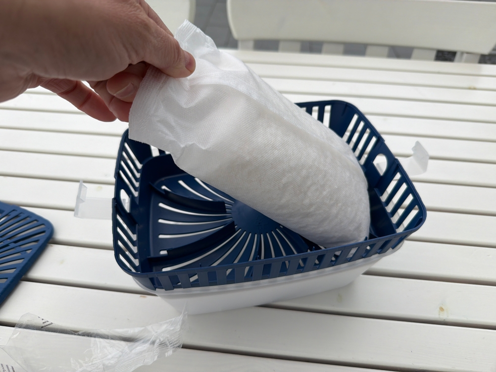 Eine Hand legt eine Packung Uhu-GmbH-&-Co.-KG-Dehumidifier in einen Luftentfeuchter