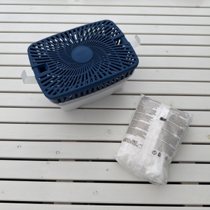 Der Uhu-Luftentfeuchter Original steht neben einer Packung mit Granulat auf einem Tisch