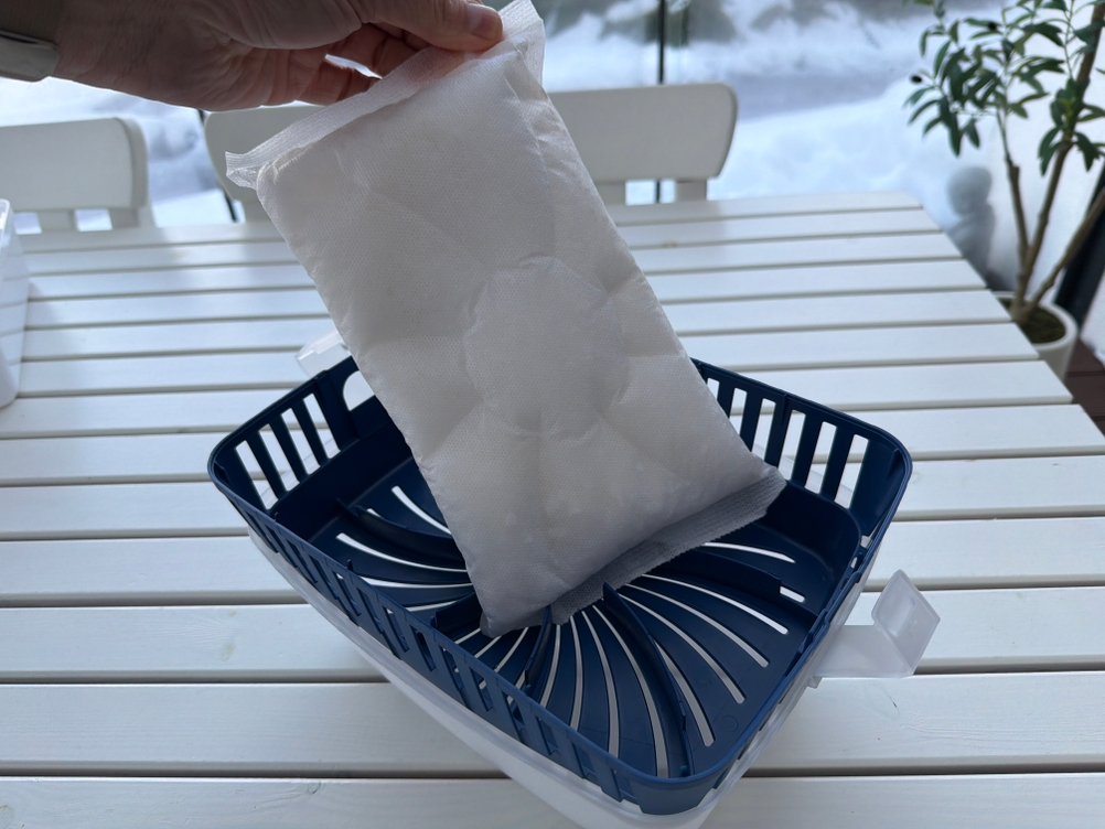 Eine Hand holt das Granulat aus dem Uhu-Luftentfeuchter Original