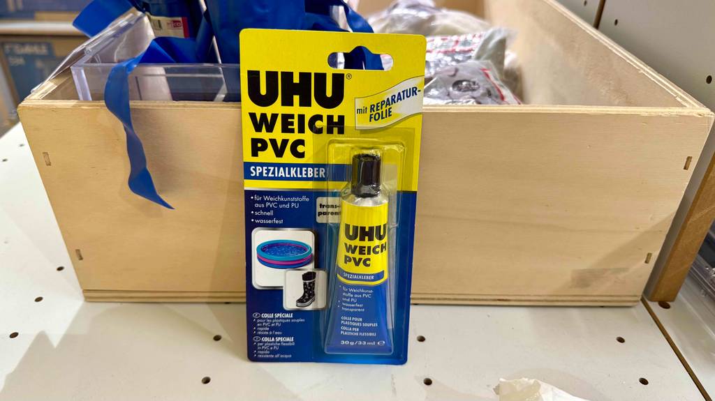 Eine Blisterpackung PVC-Kleber steht zum testen vor einer Holzkiste.