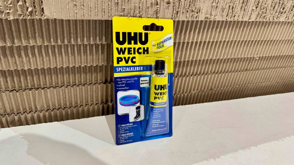 Eine im Blister verpackte Tube PVC-Kleber steht zum testen vor Wellenkartons.