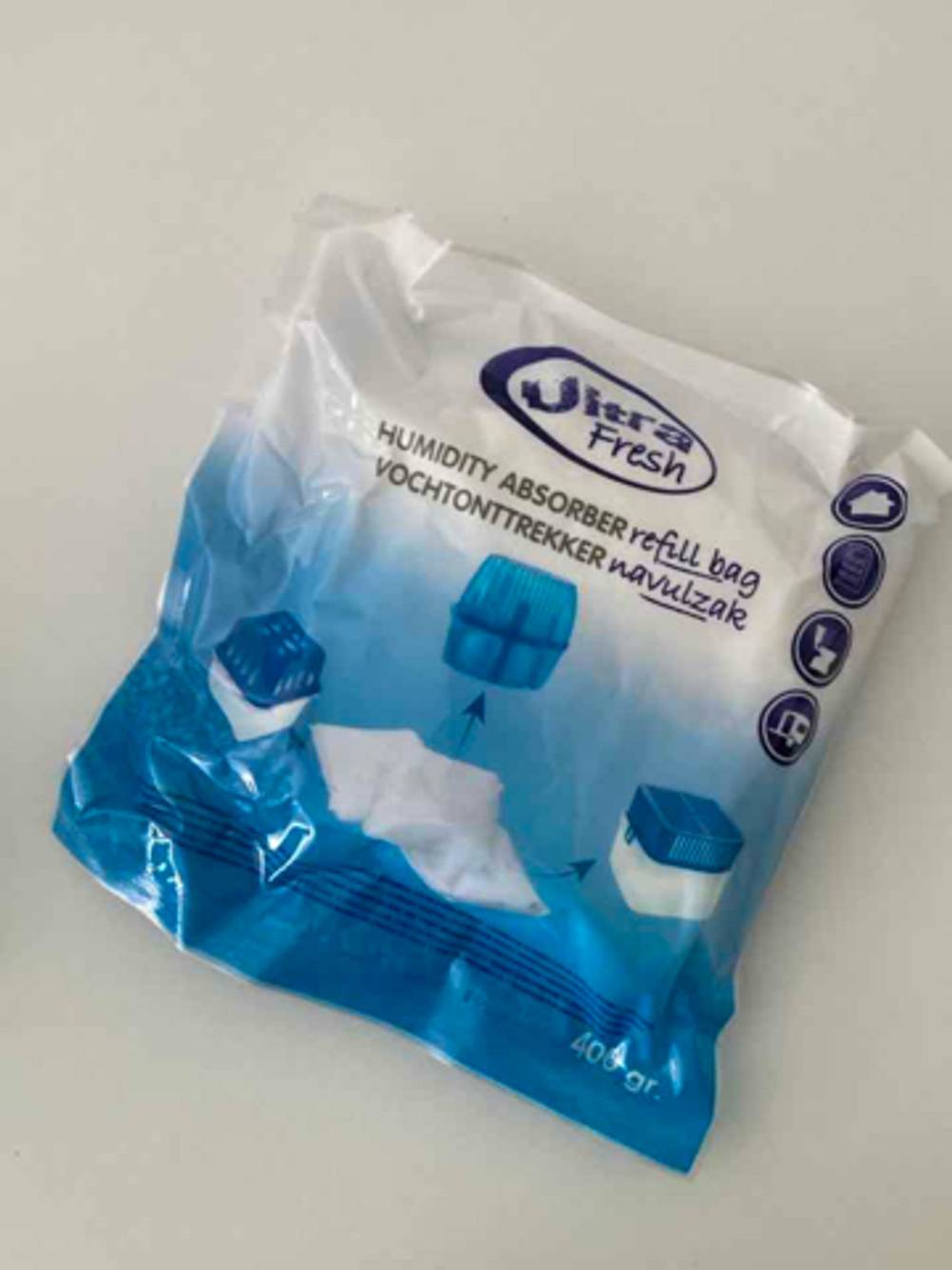 Ein weiß-blauer Kunststoffbeutel mit 400 Gramm getestetem Silica-Gel liegt auf einer weißen Oberfläche.