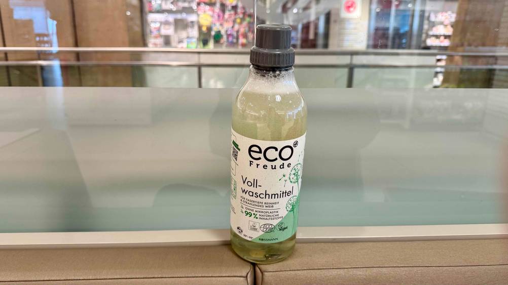 Ein Flasche des getesteten umweltfreundlichen Waschmittels steht vor einer Glasscheibe.