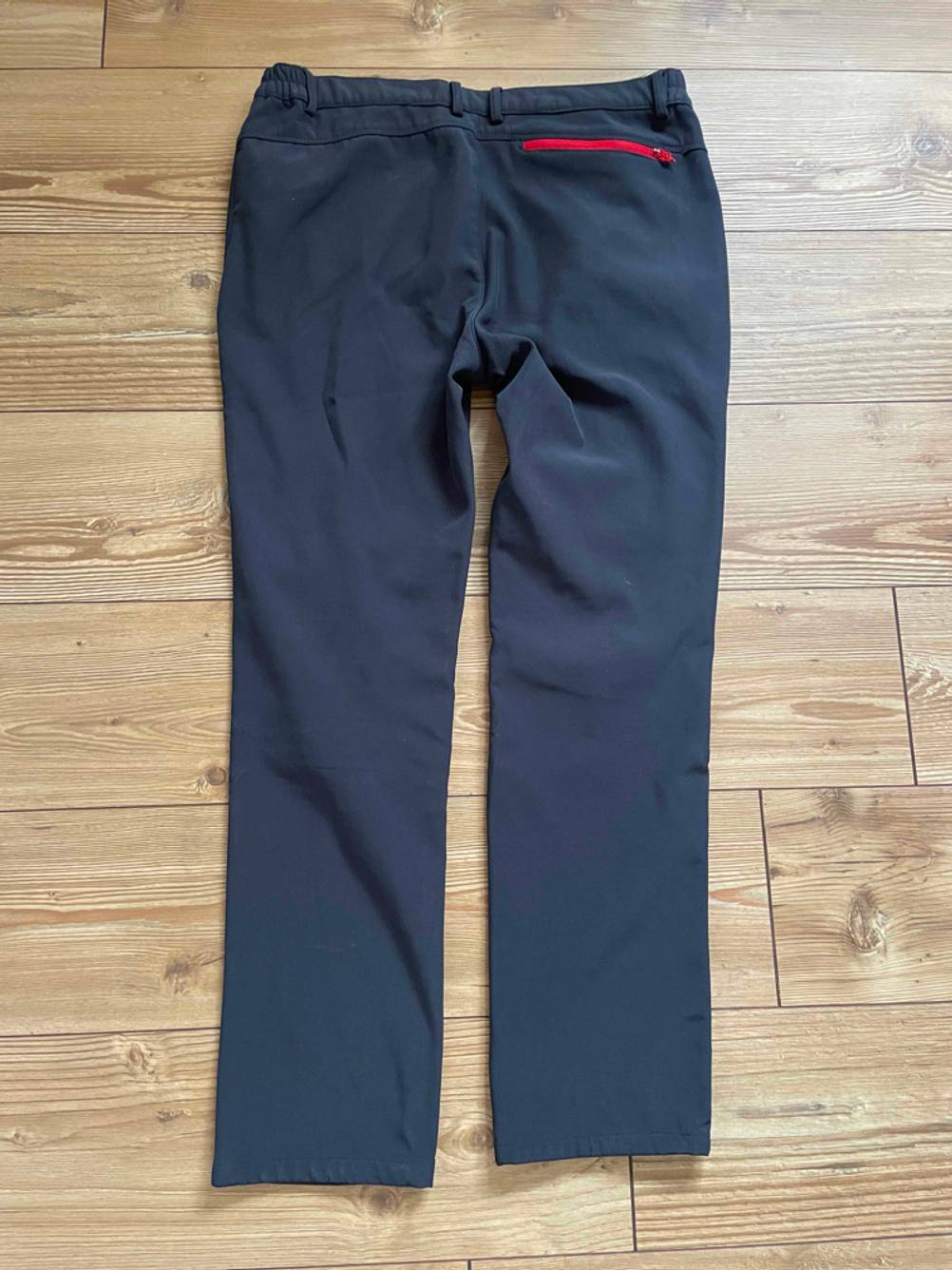 Herren-Softshellhose im Test: Eine dunkelgraue Hose liegt ausgebreitet, von hinten sichtbar, auf einer Holzoberfläche.