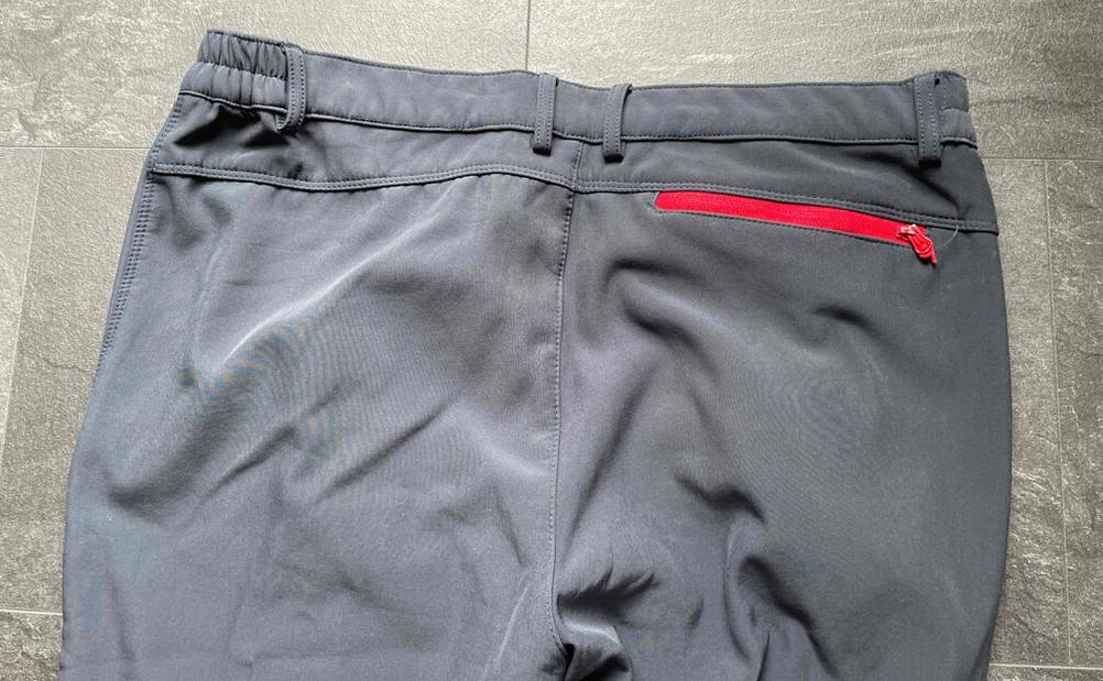 Softshellhose Herren Test: eine hellgraue Hose von hinten betrachtet, mit Fokus auf den mit Gummi versehenen Hodenbund.