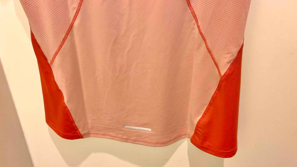 Untere Hälfte eines getesteten Laufshirts, das an einer weißen Wand hängt.