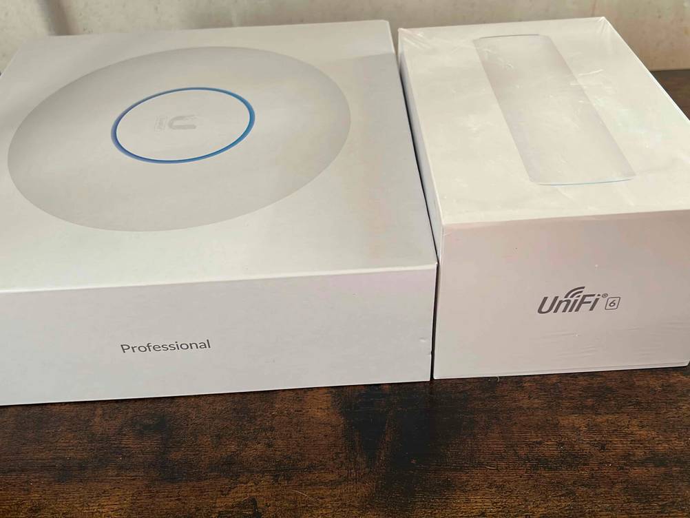 Mesh-WLAN getestet: Zwei Originalverpackungen für ein Mesh-System nebeneinander auf einer Holzfläche.
