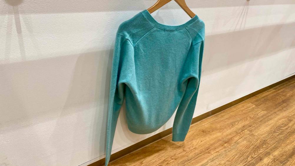 Damen-Kaschmir-Pullover-Test: Rückseite eines Kaschmir-Pullovers für Damen an einem Bügel vor einer hellen Wand hängend.