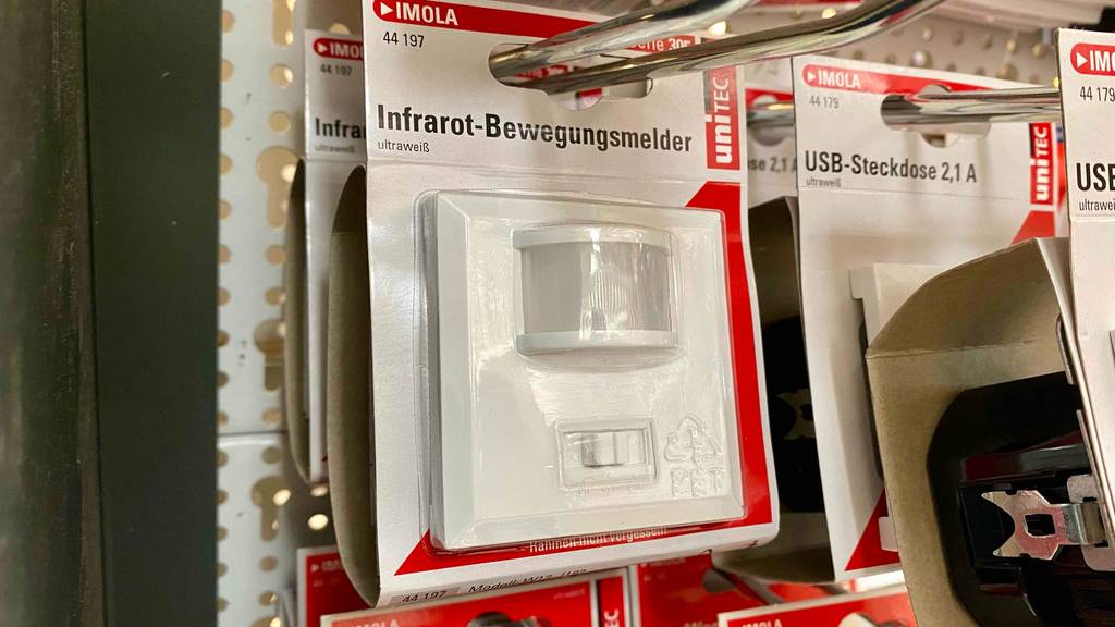 Bewegungsmelder für die Steckdose im Test: mehrere verpackte Geräte hängen hintereinander neben anderen Artikeln in einem Regal.