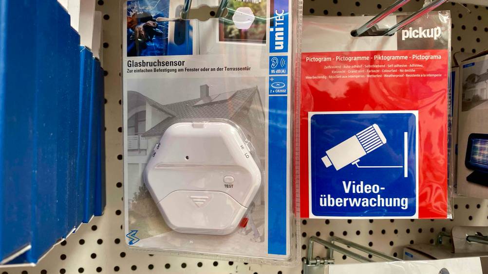 Im Test: Ein Glasbruchmelder hängt in einem Verkaufsregal neben anderen Produkten.