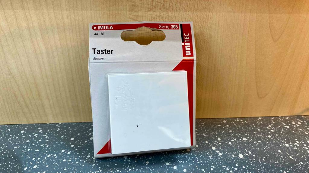 Taster im Test: ein ultraweißer Taster lehnt in seiner Verpackung an einer Holzoberfläche.