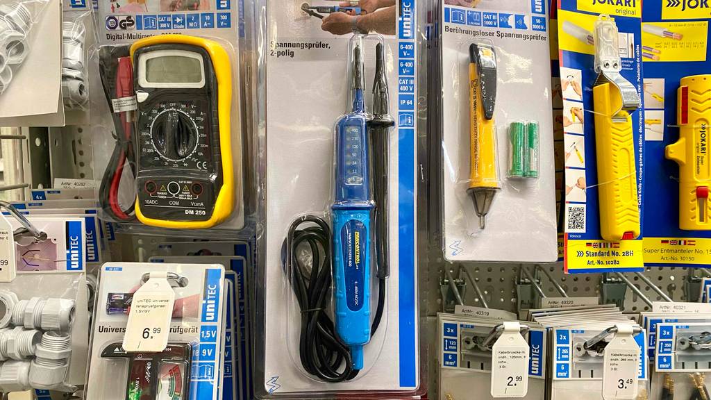 Elektrischer Unitec Spannungsprüfer im Test hängt in seiner Verpackung zusammen mit weiteren Spannungsprüfern an einem Verkaufsstand.