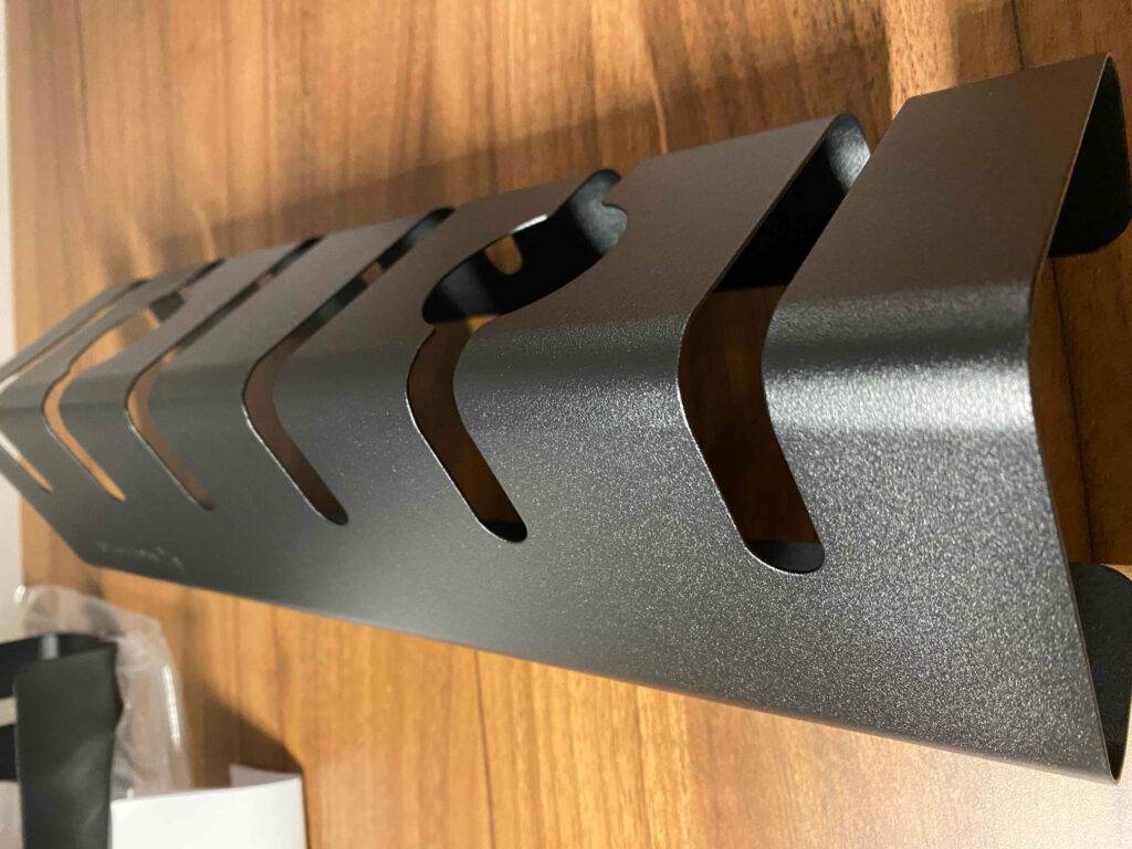 Ein schwarz satinierter, getesteter Kabelkanal aus Metall liegt auf einer Oberfläche aus Holz.