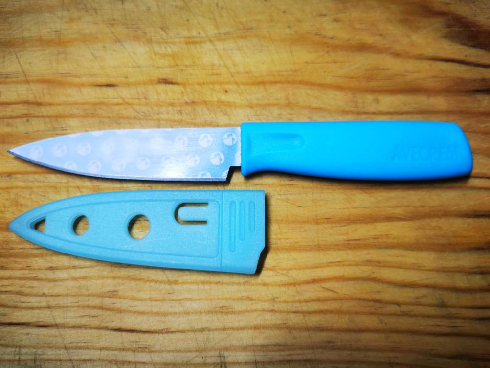 Universalmesser getestet: Ein Messer auf einer Holzfläche liegend, daneben die Schutzhülle der Klinge.