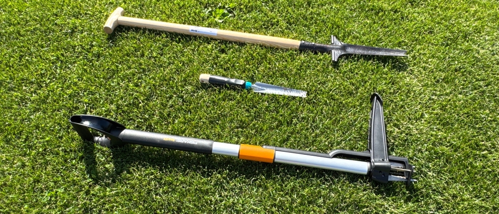 Drei Unkrautstecher liegen nebeneinander auf Gras.